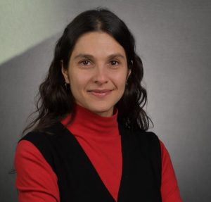 Antonella is wearing a red turtleneck and a black vest.